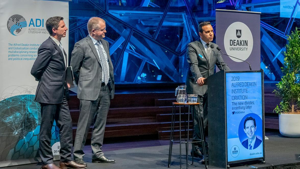 Photo of Minister Birmingham on stage with Deakin University Vice-Chancellor Professor Iain Martin and Professor Fethi Mansouri.